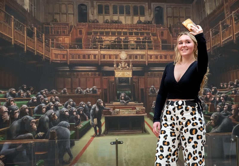 Isabelle Schofield takes a photo of herself in front of the painting ‘Devolved Parliament’ at Bristol Museum (Steve Parsons/PA)