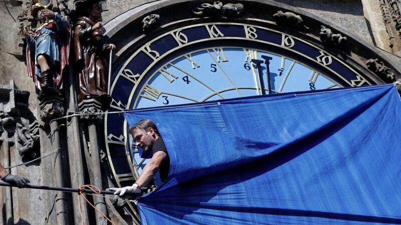 A worker walks under a cover at Prague&#39;s famed medieval astronomical clock in the picturesque Old Town Square PICTURE: Petr David Josek 