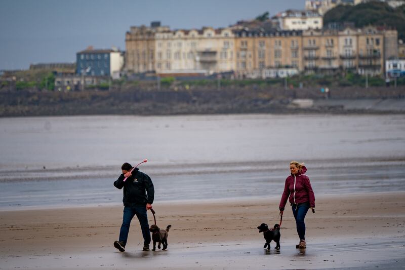 Dog walkers on the beach at Weston-super-Mare in Somerset, where strong winds hit the coast