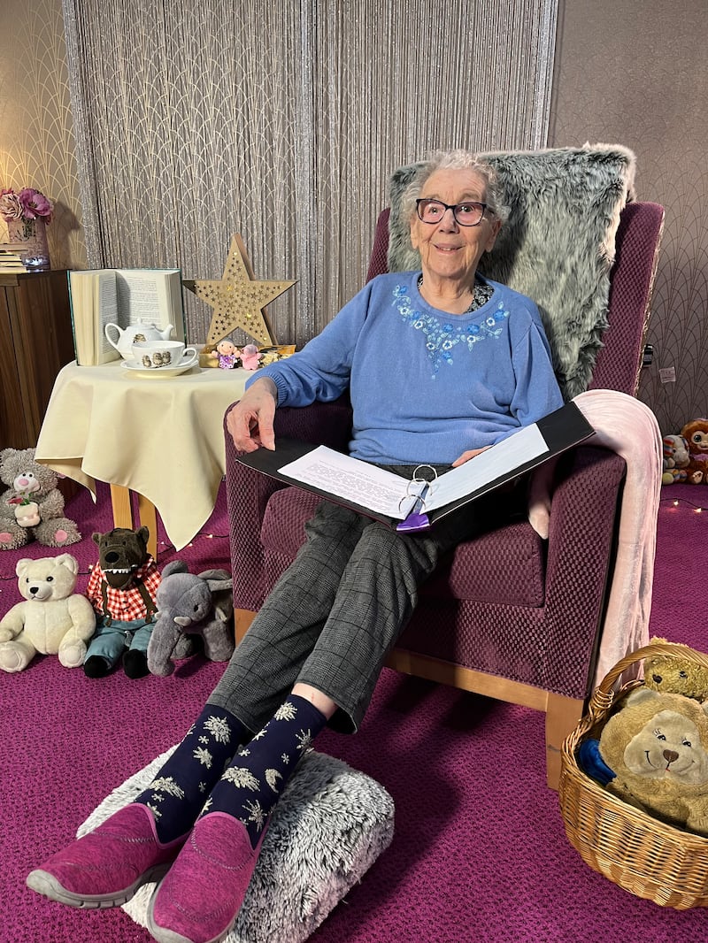 Care home resident Nancy Thompson, 86 reads The Three Little Pigs on the care home's 'storytelling throne'..