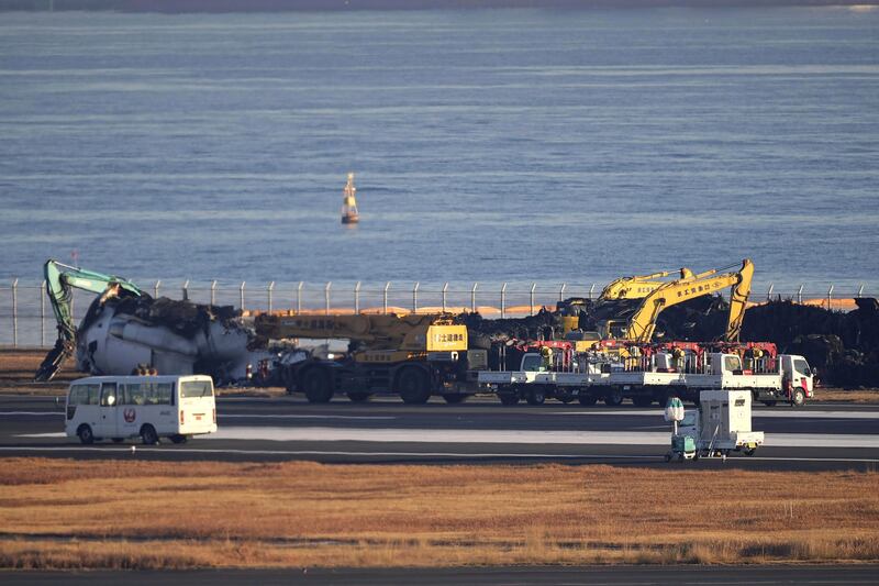 Heavy machinery removes the debris of the burned Japan Airlines plane (Kyodo News/AP)