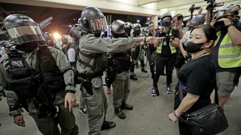 Police in riot gear ask a woman to take off her mask outside a train station in Hong Kong. Picture by Dita Alangkara/AP 