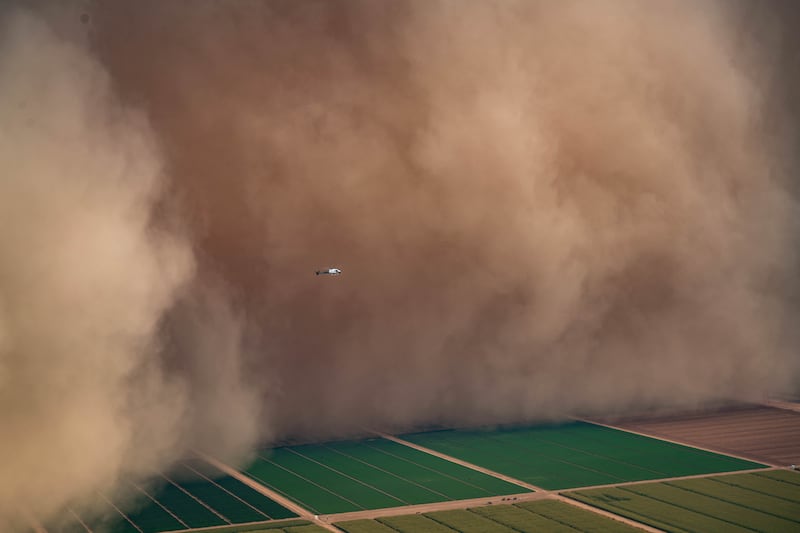 Another team's helicopter is dwarfed by a dust storm