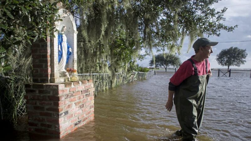 Gerard Braud walks across his front yard near a statue of Mary as the lakefront deals with the strong wind and water effects from Tropical Storm Harvey on Wednesday PICTURE: Chris Granger/NOLA.com The Times-Picayune via AP 