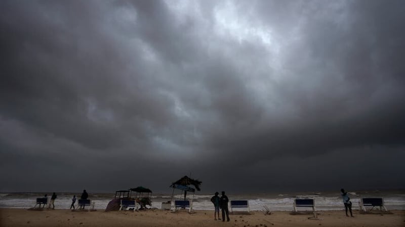Rain clouds fill the sky as people stand on a beach ahead of cyclone Biparjoy’s landfall at Mandvi in Kutch district of Gujarat state, India (Ajit Solanki/AP/PA)