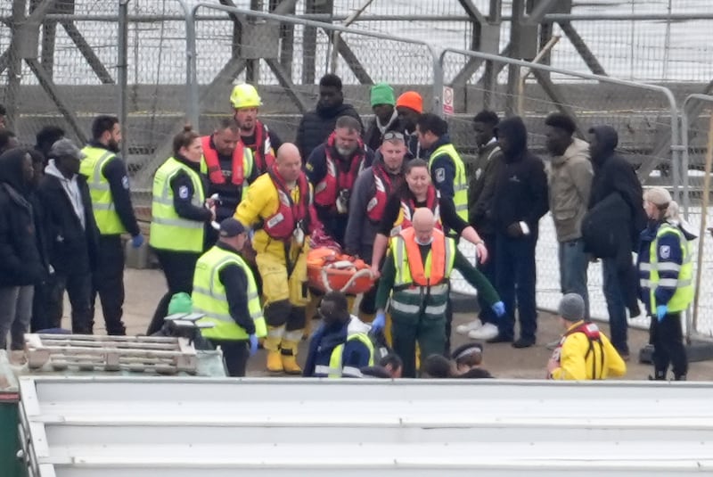 Crews carried someone ashore on a stretcher as migrants arrived in Dover on Tuesday