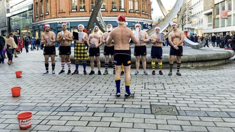 Topless rugby players sing for charity in Belfast city centre yesterday 