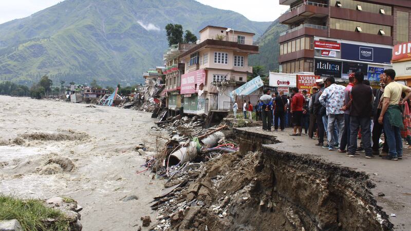People stand by a road washed away by the River Beas in Kullu District, Himachal Pradesh, India (Aqil Khan/AP)