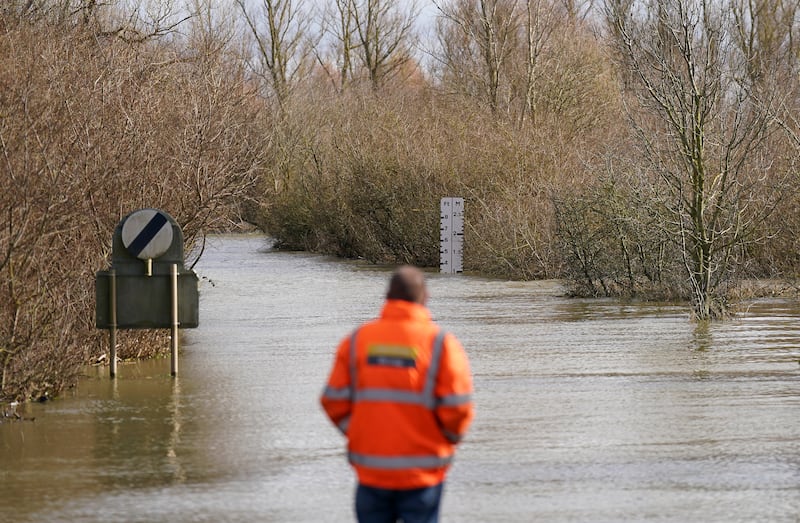 A local resident looks along the flooded A1101 in Welney, Norfolk