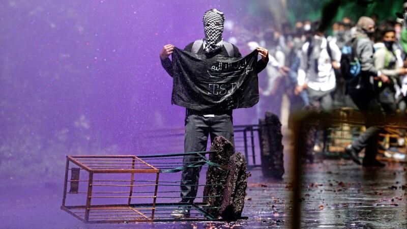 A Kashmiri student holds a black flag as Indian police use coloured water to disperse them as they clash in Srinagar, Indian controlled Kashmir on Monday. Tensions between Kashmiri students and Indian law enforcement have escalated since April 15, when government forces raided a college in Pulwama, about 30 kilometers (19 miles) south of Srinagar, to scare anti-India activists PICTURE: Mukhtar Khan/AP 