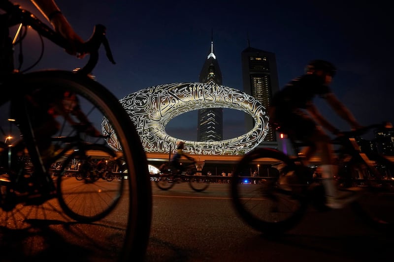 Cyclists ride past the Museum of the Future and Emirates Towers in Dubai