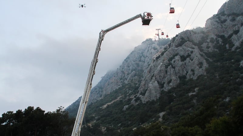 A rescue team helps passengers on the cable car (IHA via AP)